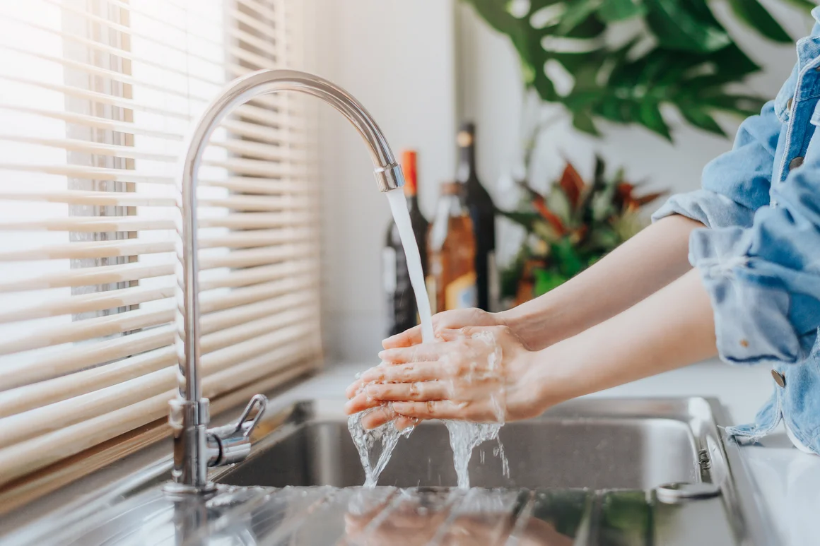 Person wäscht Hände unter Wasserhahn
